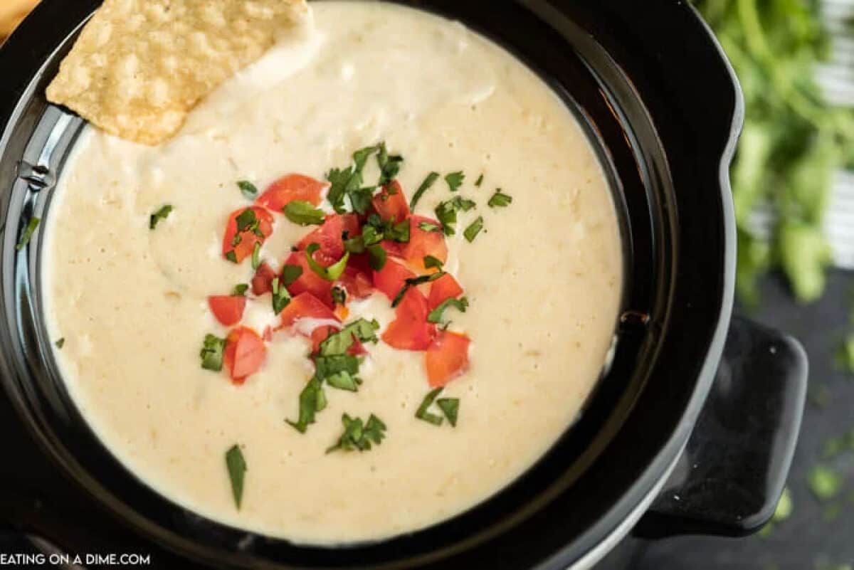 Close up of white cheese dip in a small black crock pot 