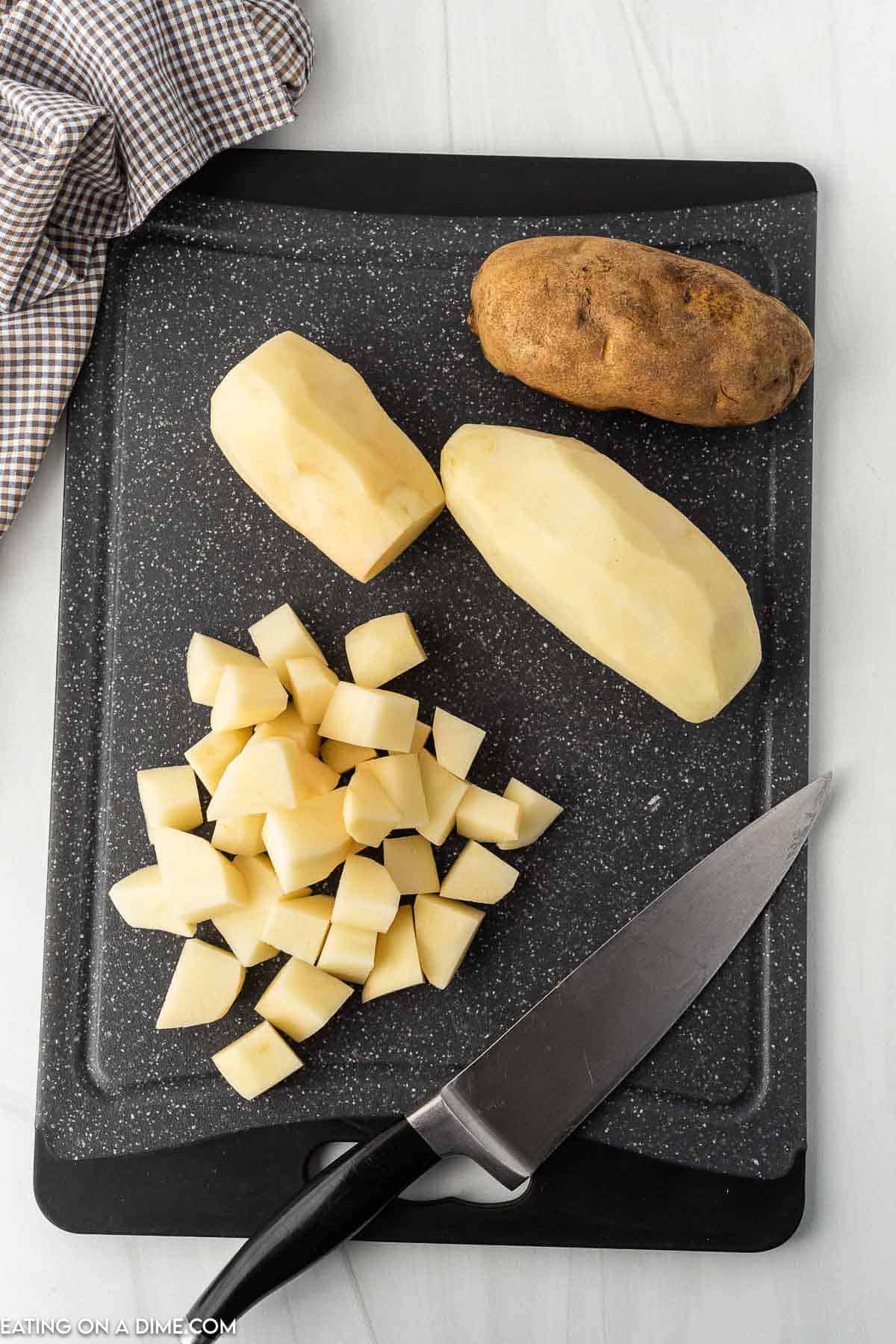 Peeled potatoes on a cutting board and dicing potatoes into small pieces