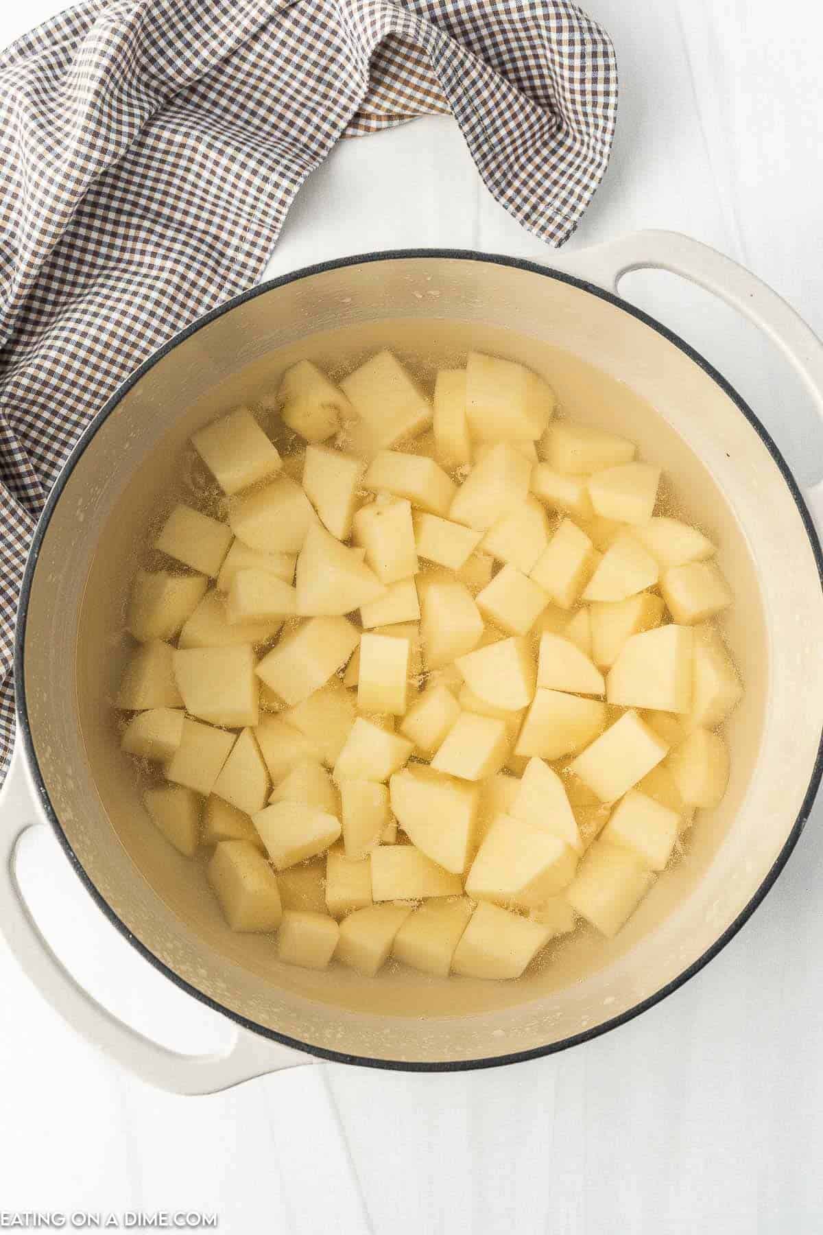 Placing diced potatoes in a large pot of water