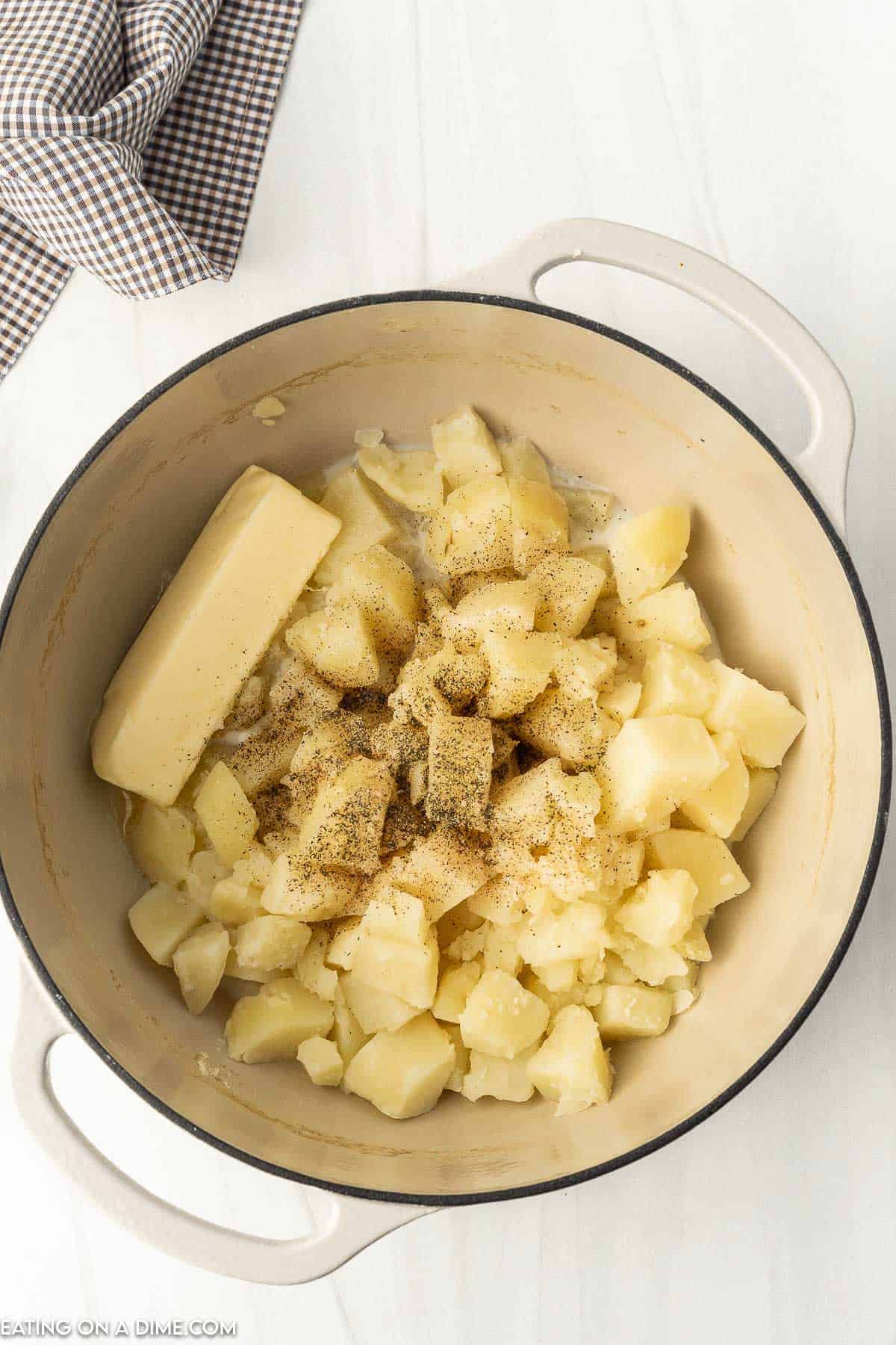 Placed drained cooked diced potatoes in a large pot with a stick of butter and salt and pepper