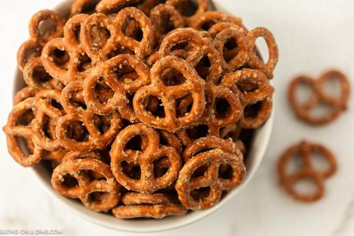 Close up of a bowl of ranch pretzels with a few on the counter next to the bowl. 