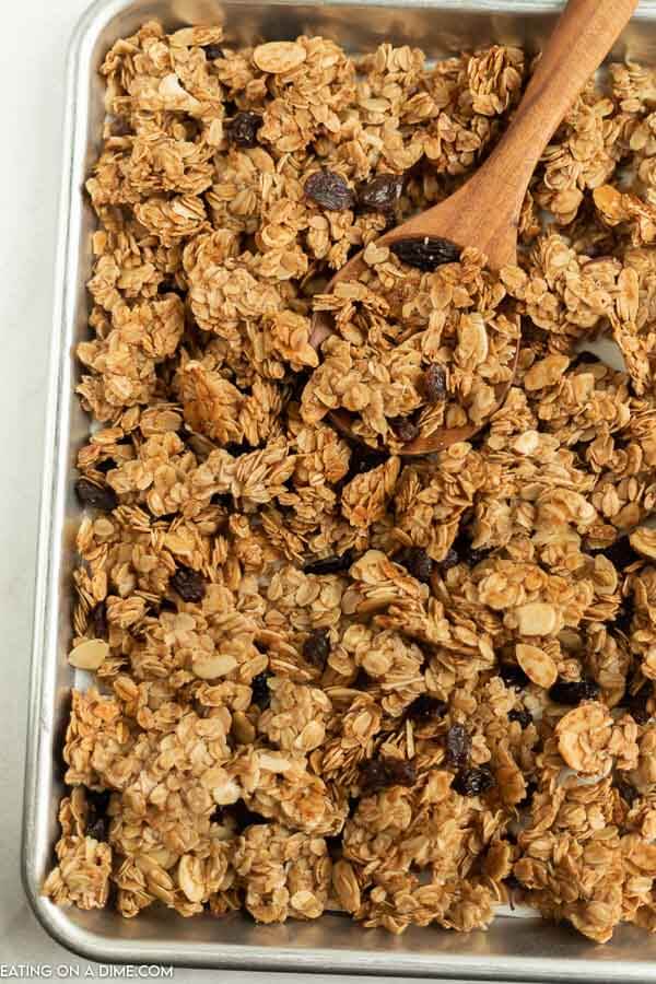 Close up image of homemade granola on a baking sheet with a wooden spoon 