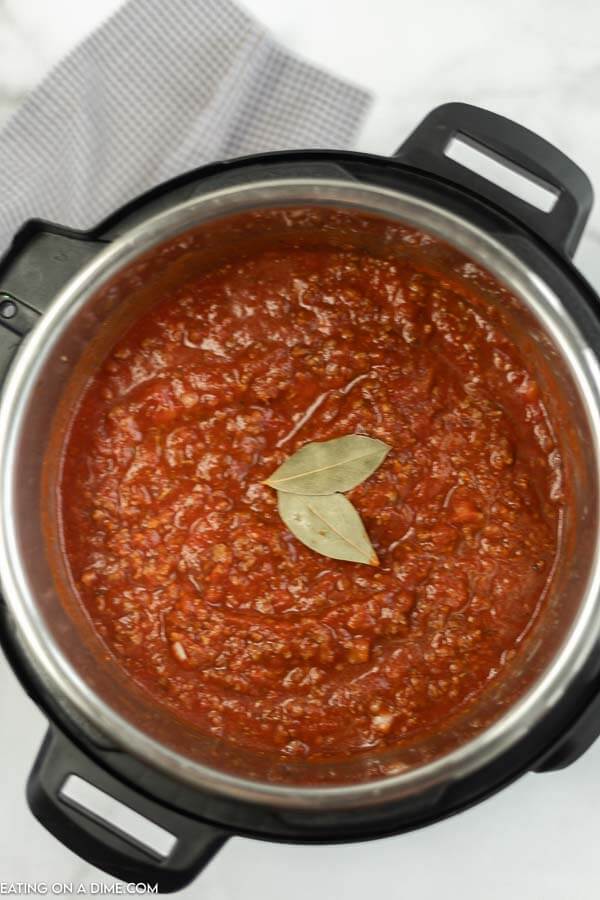 close up image of spaghetti sauce in an instant pot with basil leaves on top. 