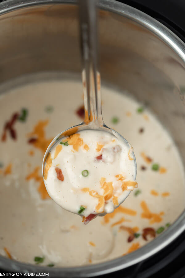 Close up image of cooked cauliflower soup in the instant pot and a serving on a ladle. 