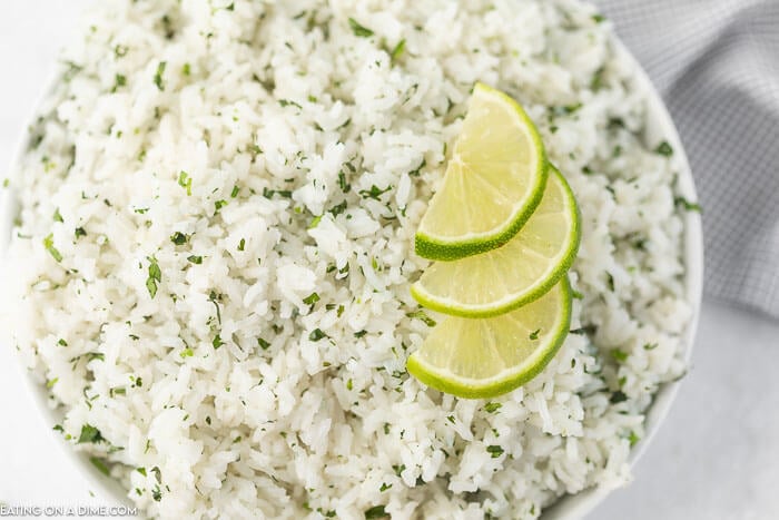 Close up image of a bowl of cilantro lime rice with slice limes on top. 