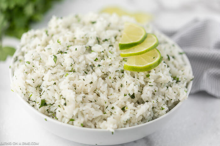 Close up image of a bowl of cilantro lime rice with slice limes on top. 