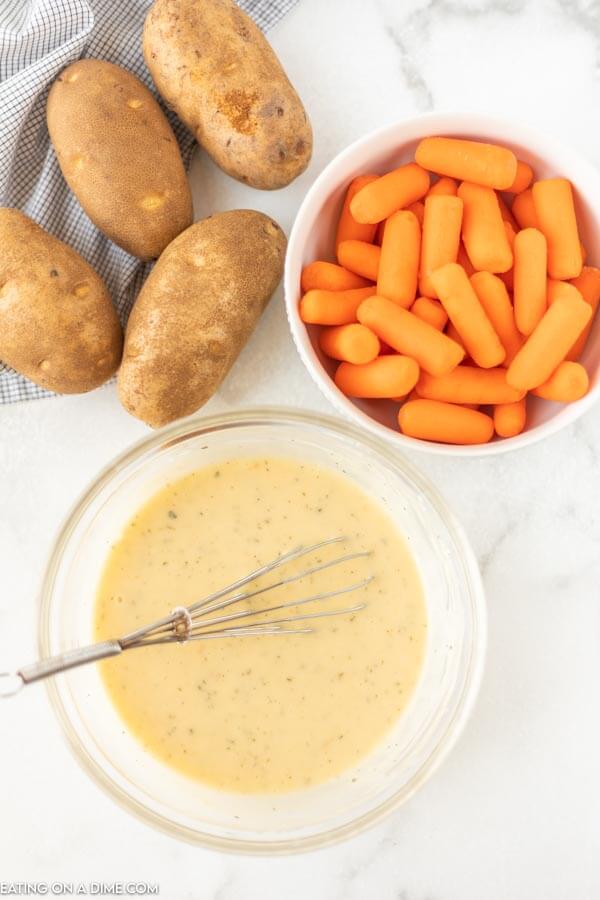 close up image of potatoes, carrots and the creamy sauce in a bowl. 