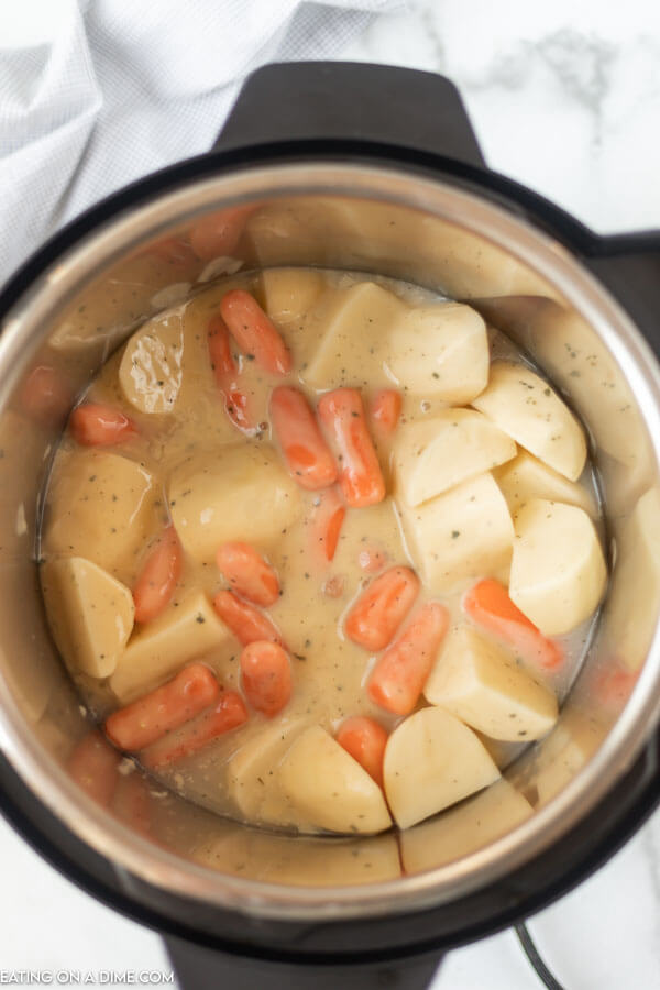 Close up image of potatoes and carrots in a creamy sauce in the instant pot. 