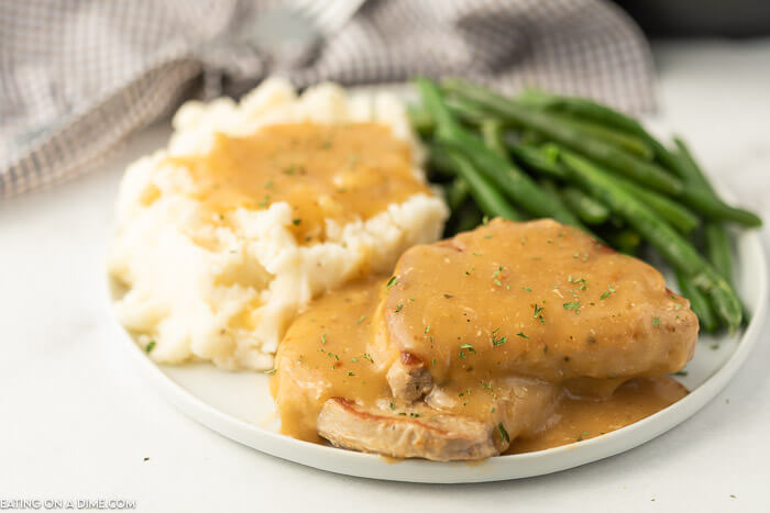 Plate of pork chops with gravy and mashed potatoes and green beans. 