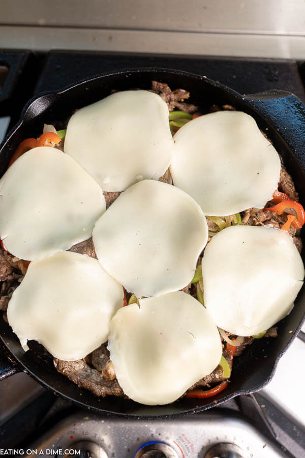Close up image of Philly Cheesesteak in a iron skillet with provolone on top.