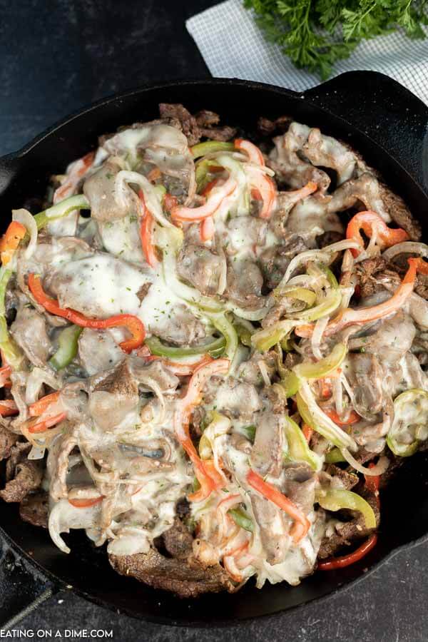 Close up image of philly cheesesteak in a iron skillet. 