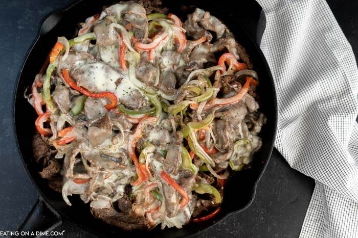 Close up image of philly cheesesteak in a iron skillet. 