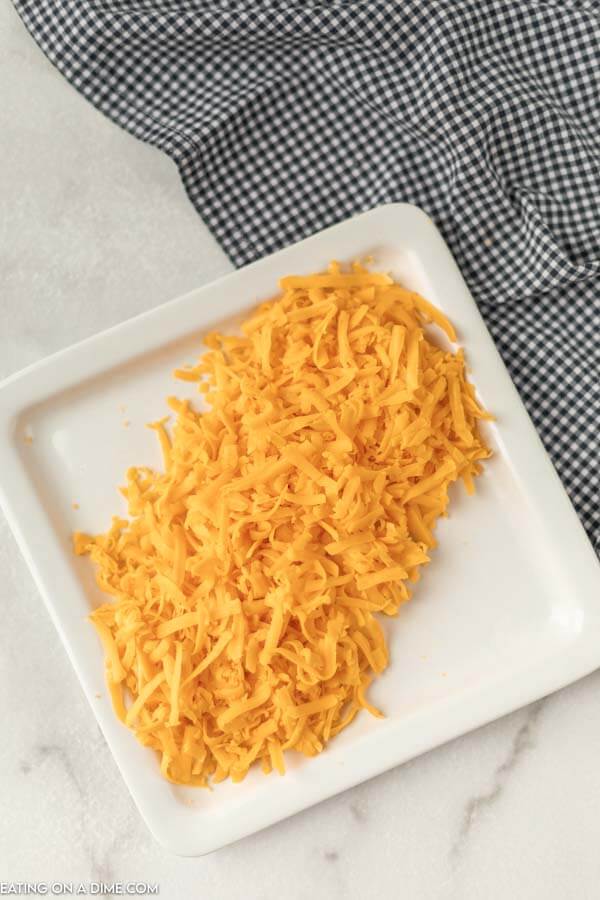 Close up image of shredded cheese on a white plate. 