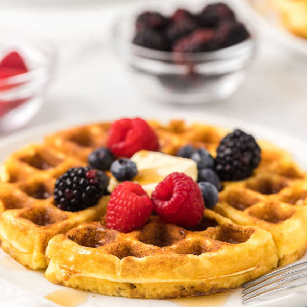 Keto waffle on plate topped with fruit and butter.