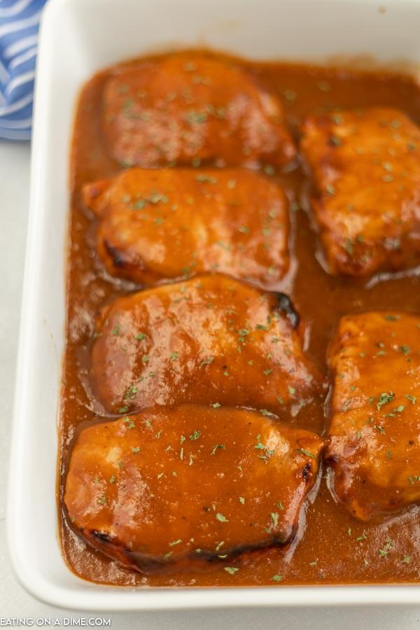 Close up image of pork chops covered in coke marinade in a white pan. 