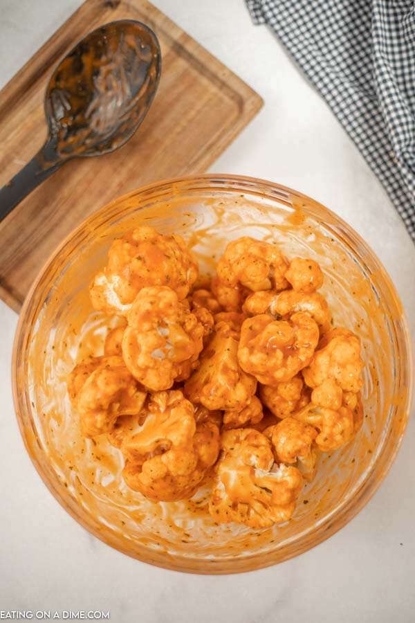 Close up image of buffalo cauliflower being mixed in a bowl 
