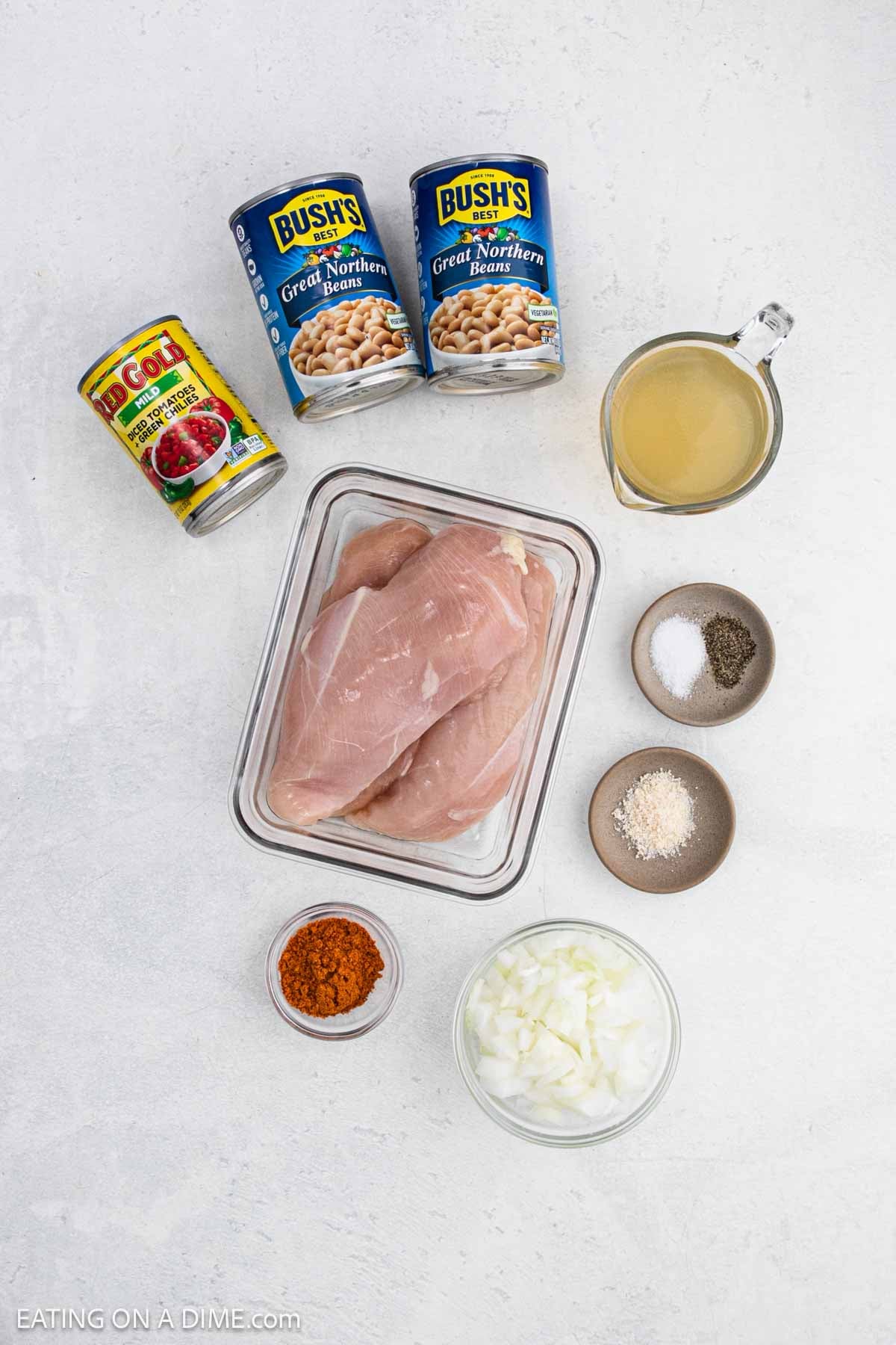 Ingredients needed to make this recipe which includes chicken, white beans, Rotel, chicken broth, chopped onions, and spices.