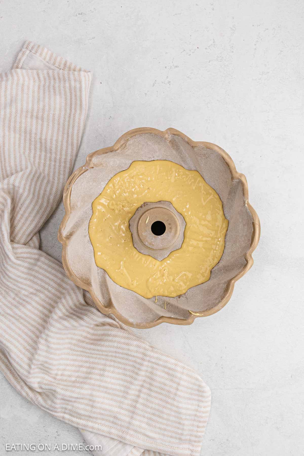 A portion of the cake batter in the flour dusted bundt pan.
