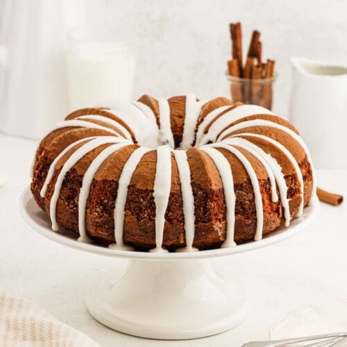 Cinnamon bundt cake topped with a icing on a cake pan.