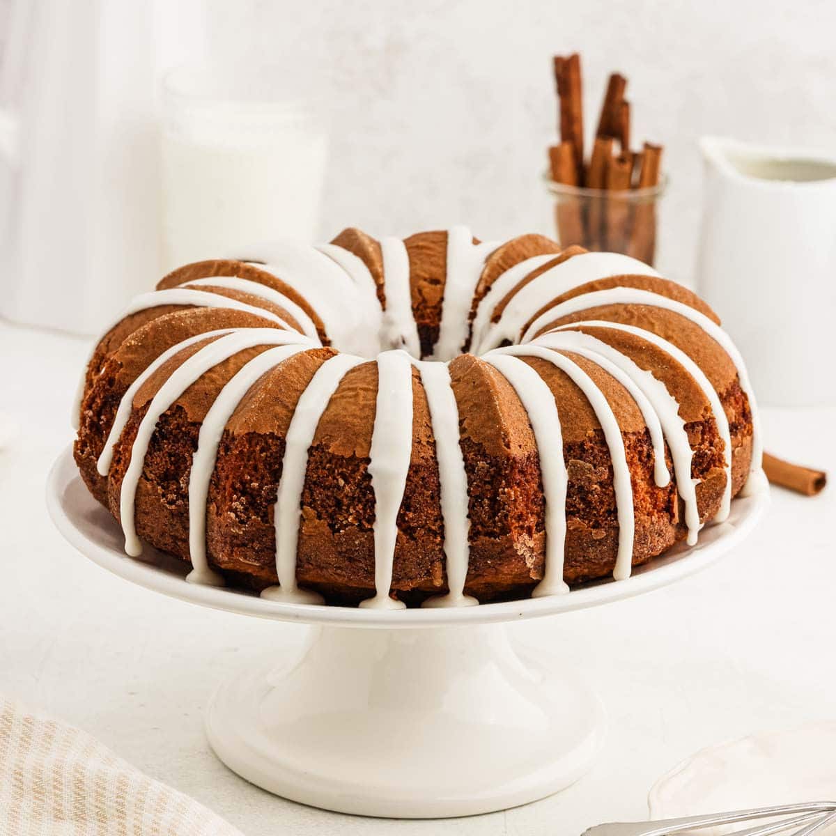 Cinnamon bundt cake topped with a icing on a cake pan.