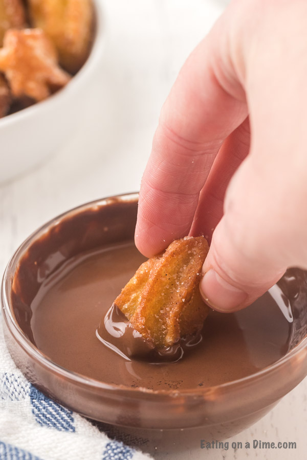 Close up image of dipping churros in chocolate. 
