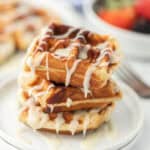 A stack of cinnamon roll waffles with icing on top.