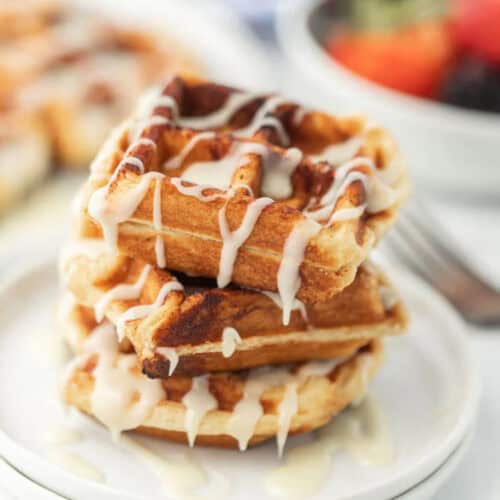 A stack of cinnamon roll waffles with icing on top.