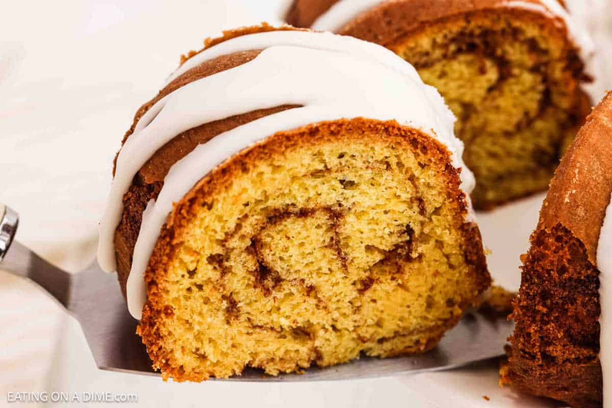 A serving of a Cinnamon Bundt Cake on a spatula topped with icing. 