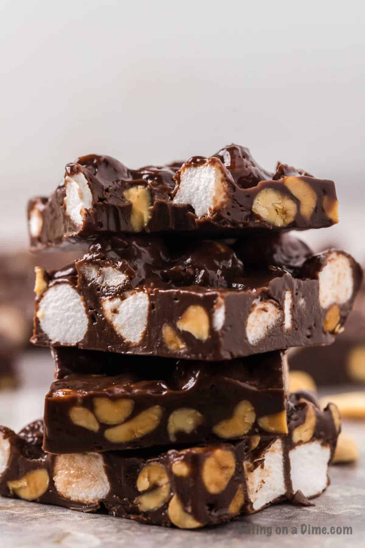 A stack of rocky road fudge pieces is shown with a close-up view, highlighting chunks of marshmallows and nuts embedded in rich, glossy chocolate. The background is blurred, making the fudge the clear focal point of the imageโperfect for anyone seeking an easy rocky road fudge recipe.