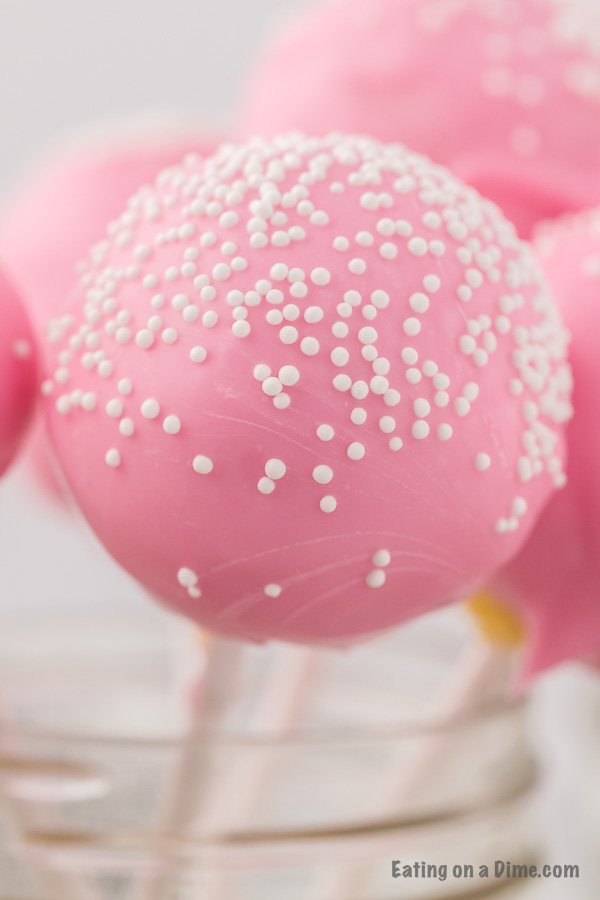 Close up image of a pink cake ball with white sprinkles. 