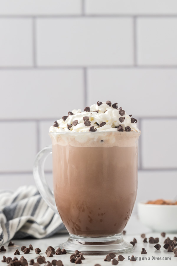 Clear mug with hot cocoa topped with whipped cream and chocolate chips. 