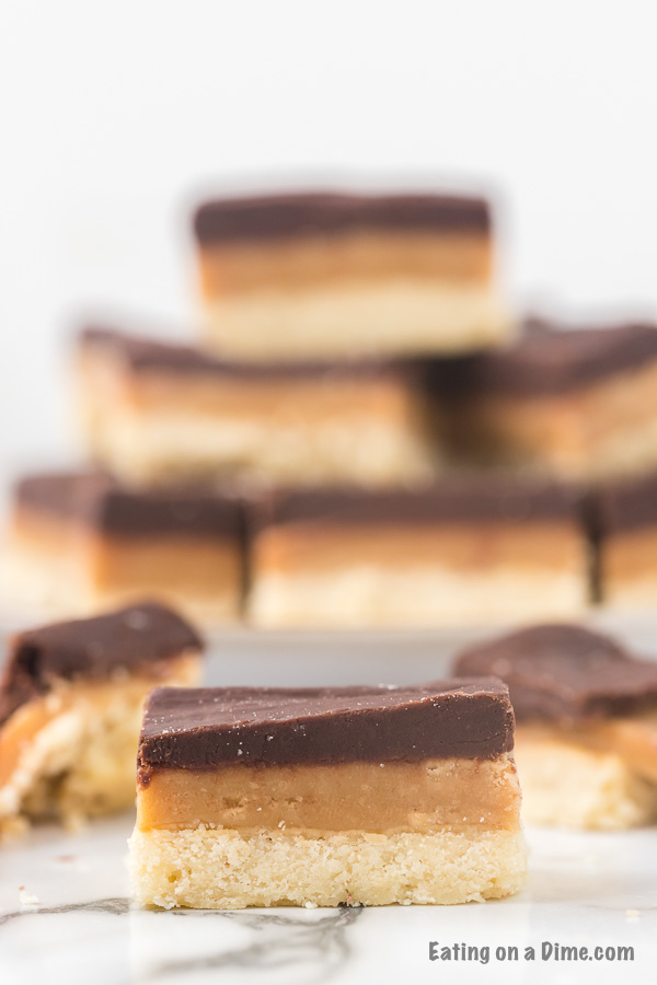 Close up image of Homemade Twix bars. The a plate of twix bars in the background. 