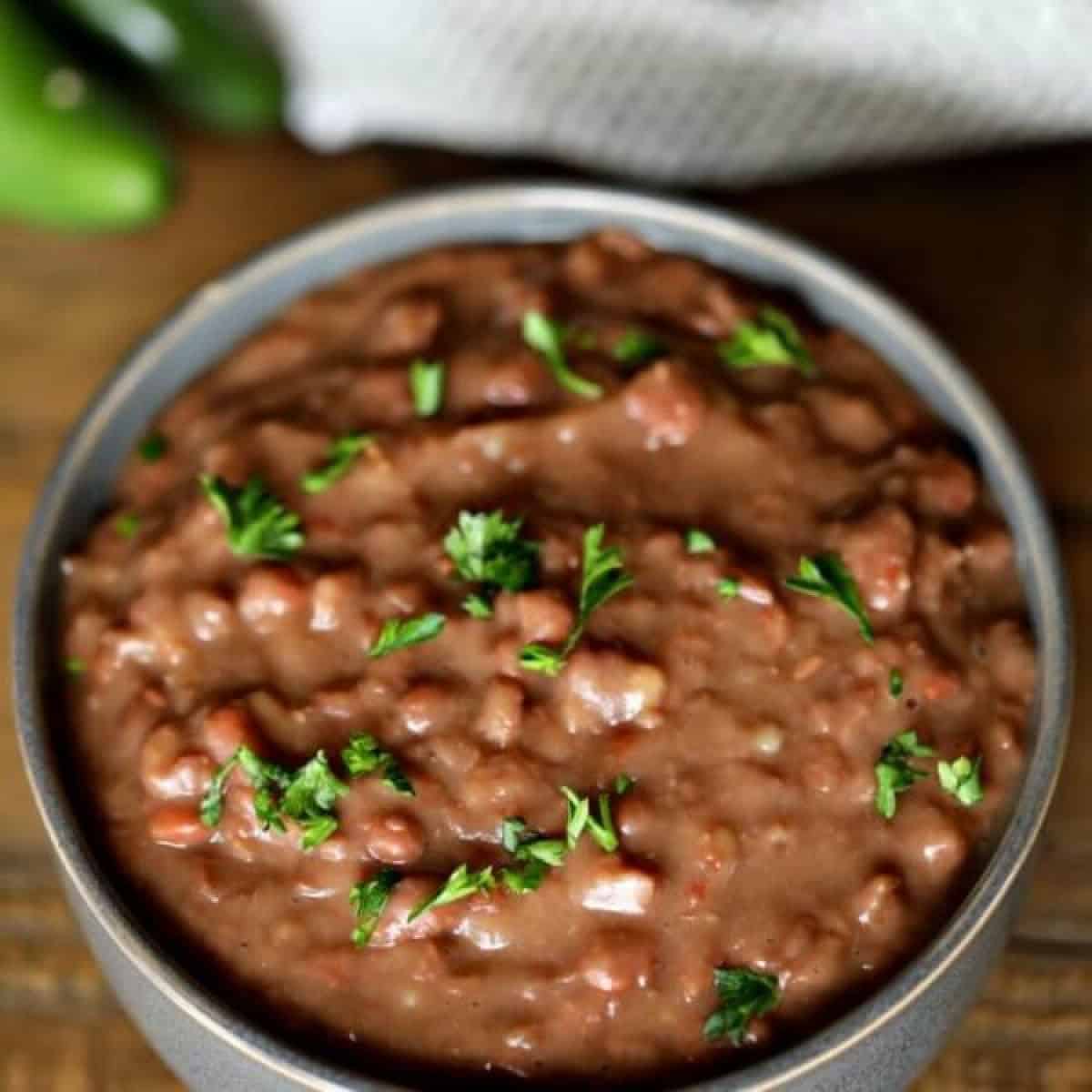 Learn how to make refried beans by cooking them in the crockpot! It is so easy to make Crock Pot refried beans and saves a ton of money.