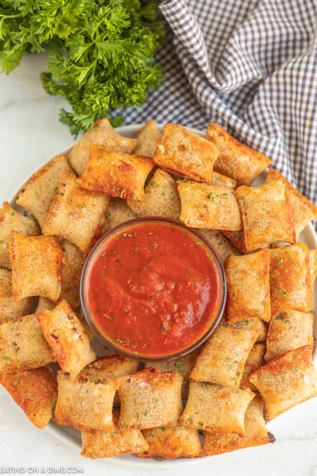 Pizza rolls on a platter with pizza sauce.