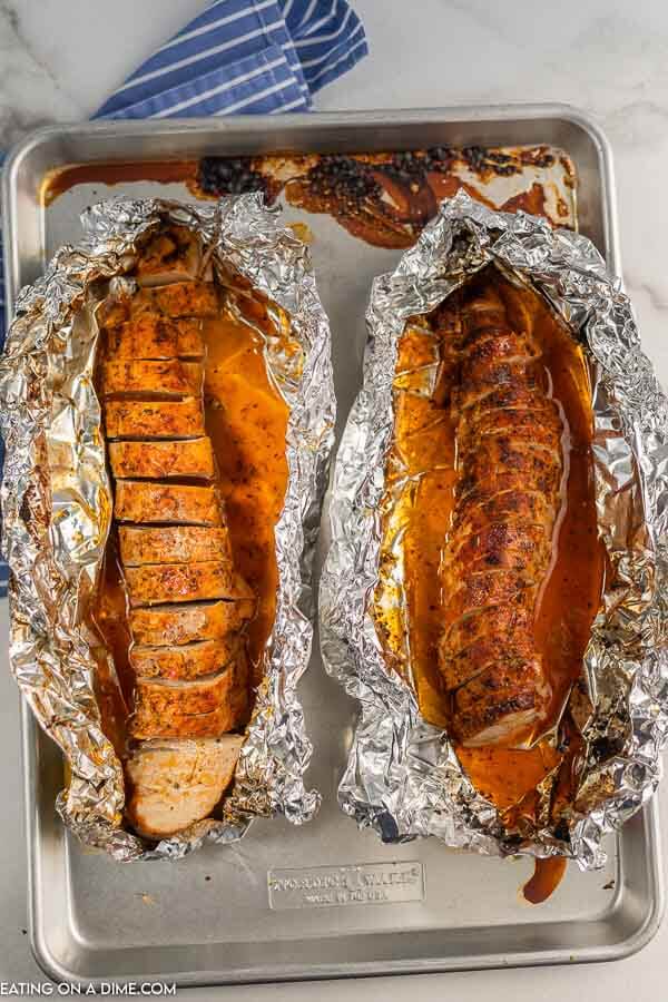 2 pieces of baked pork tenderloin on a baking sheet it the center of 2 pieces of foil 
