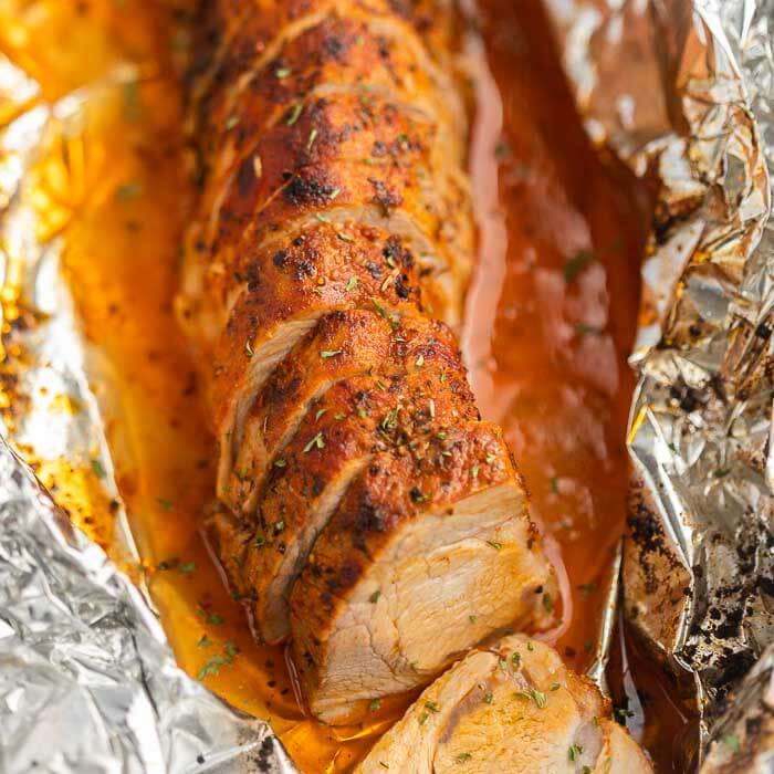 Close up of the sliced baked pork tenderloin on a piece of foil with the pork juices around it 