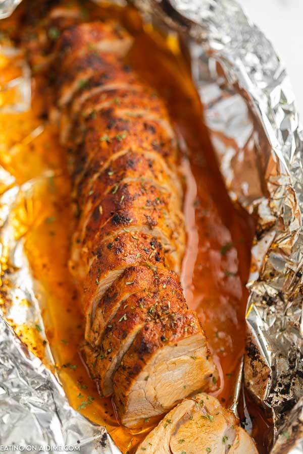 Sliced Baked Pork Tenderloin sitting in the middle of a piece of foil 