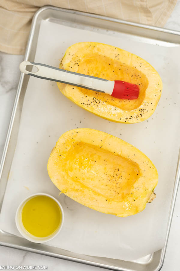Close up image of putting olive oil and salt and pepper on spaghetti squash. 