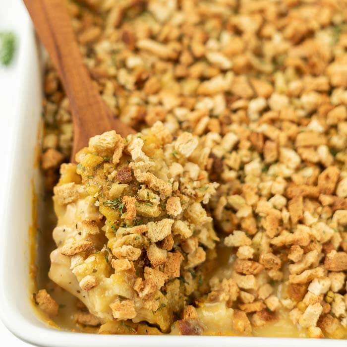 Chicken stuffing bake in casserole dish with serving spoon. 