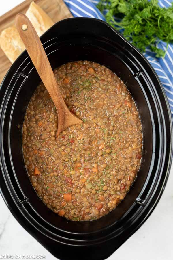 Lentil Soup in the slow cooker with a wooden spoon