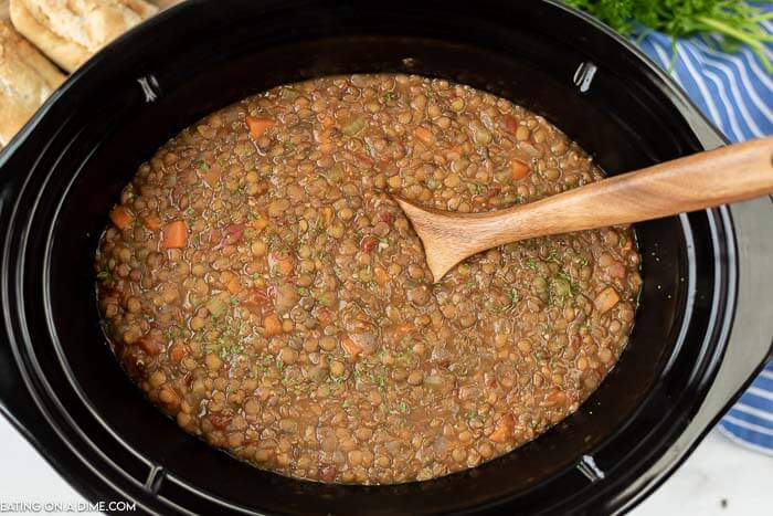Lentil soup in the slow cooker with a wooden spoon