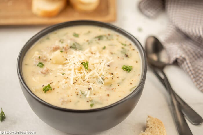 Close up image of Zuppa Toscana in a black bowl with two spoons. 