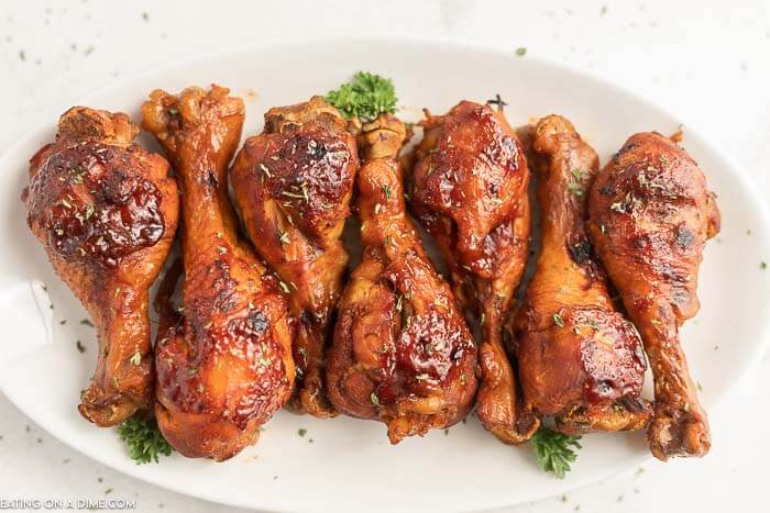 Cooked Chicken Drumsticks on a white platter topped with fresh parsley 