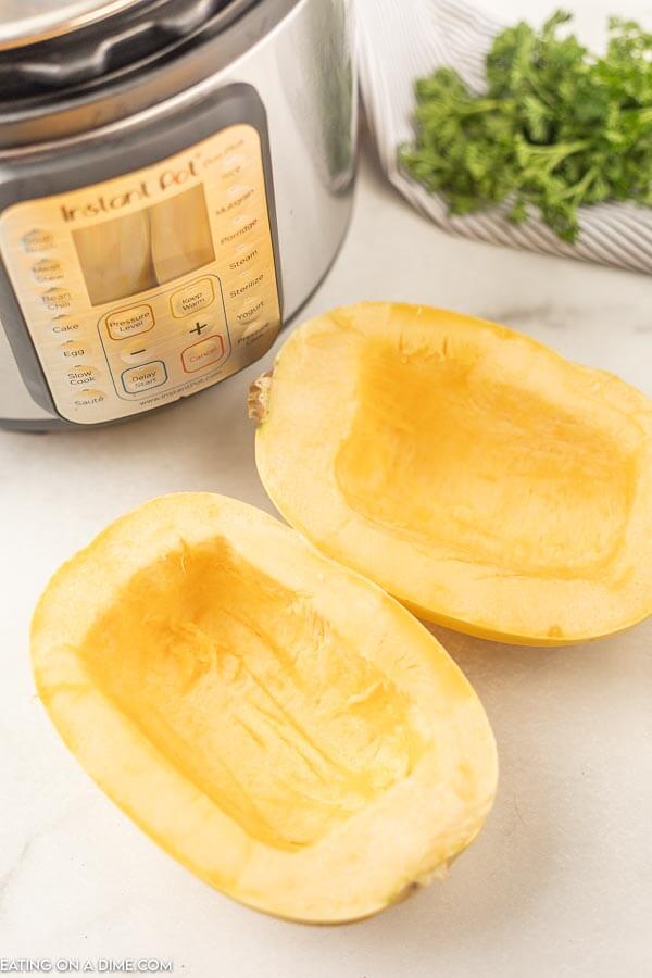 Close up image of uncooked spaghetti squash on the table with instant pot in the background. 