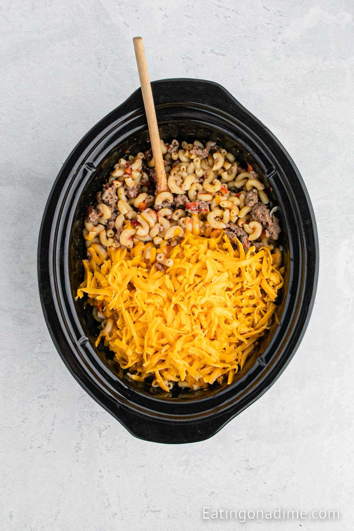 Topping the hamburger helper with shredded cheese