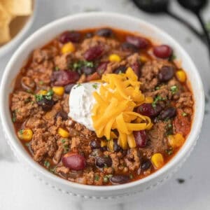 Taco soup in a bowl topped with sour cream and shredded cheese.
