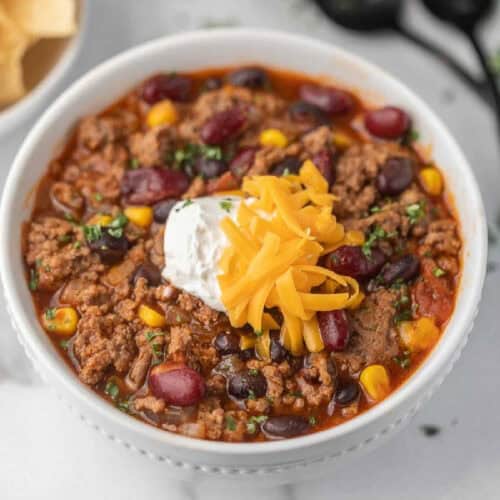 Taco soup in a bowl topped with sour cream and shredded cheese.