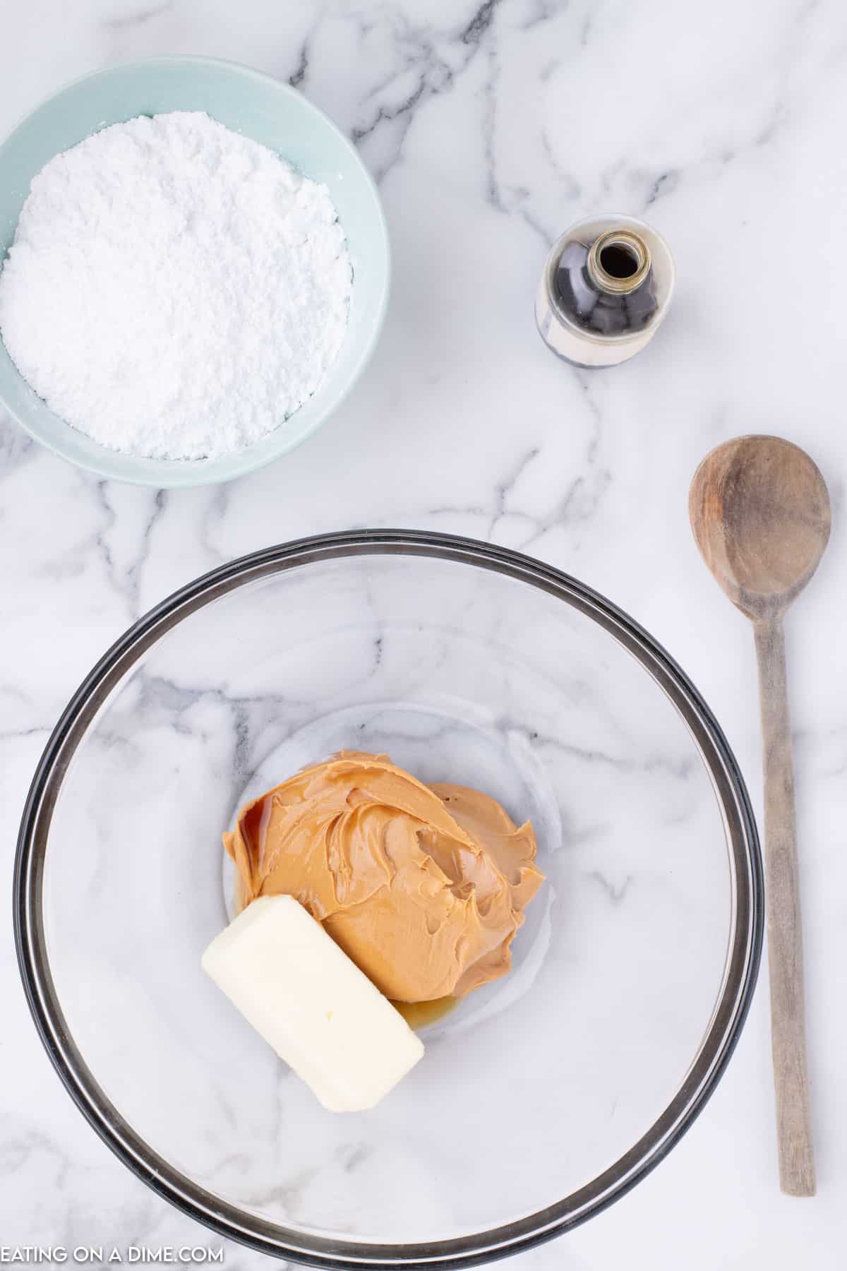 Combining butter and peanut butter in a bowl with a small bowl of powdered sugar on the side