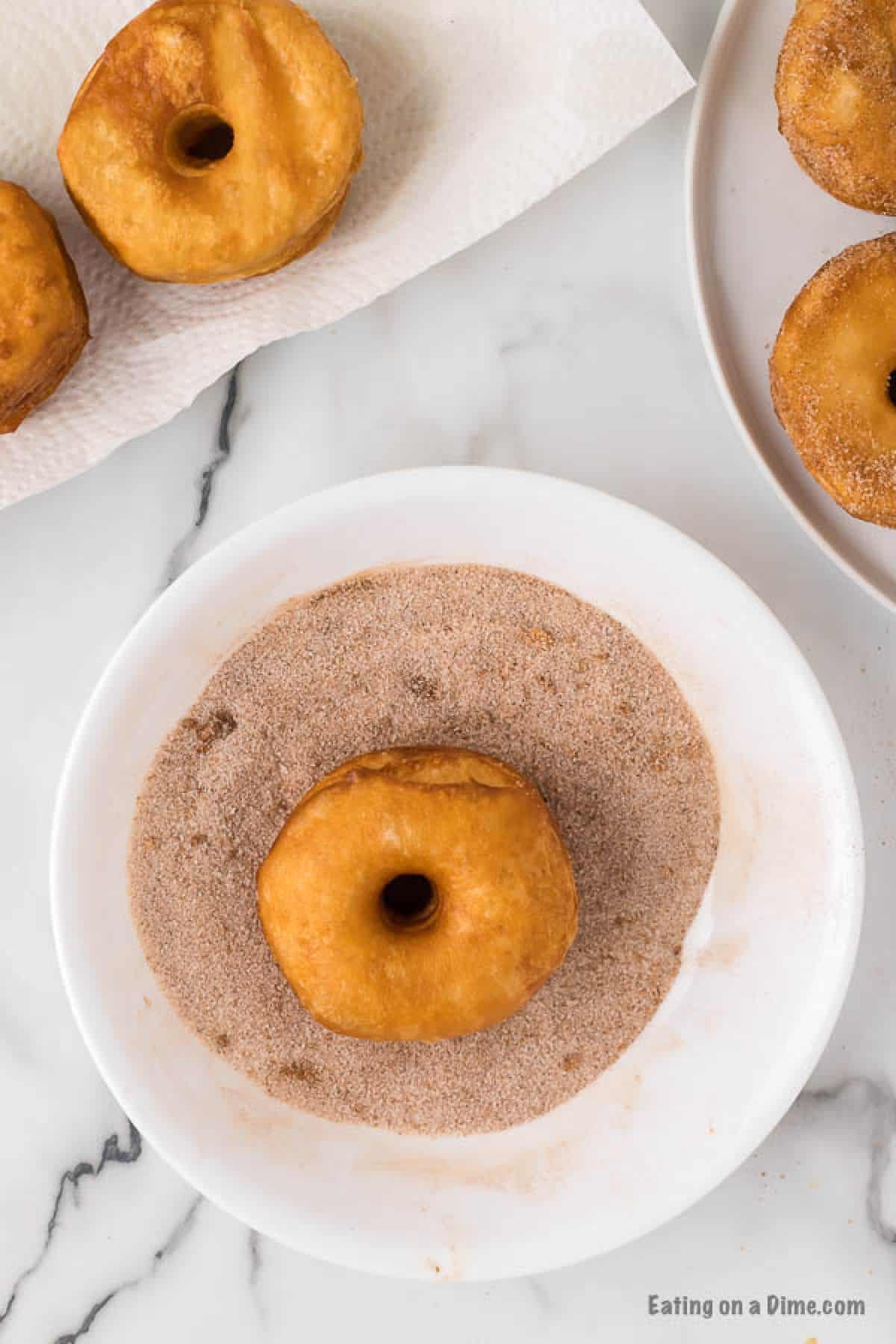 Cooked donuts in the bowl of cinnamon and sugar.