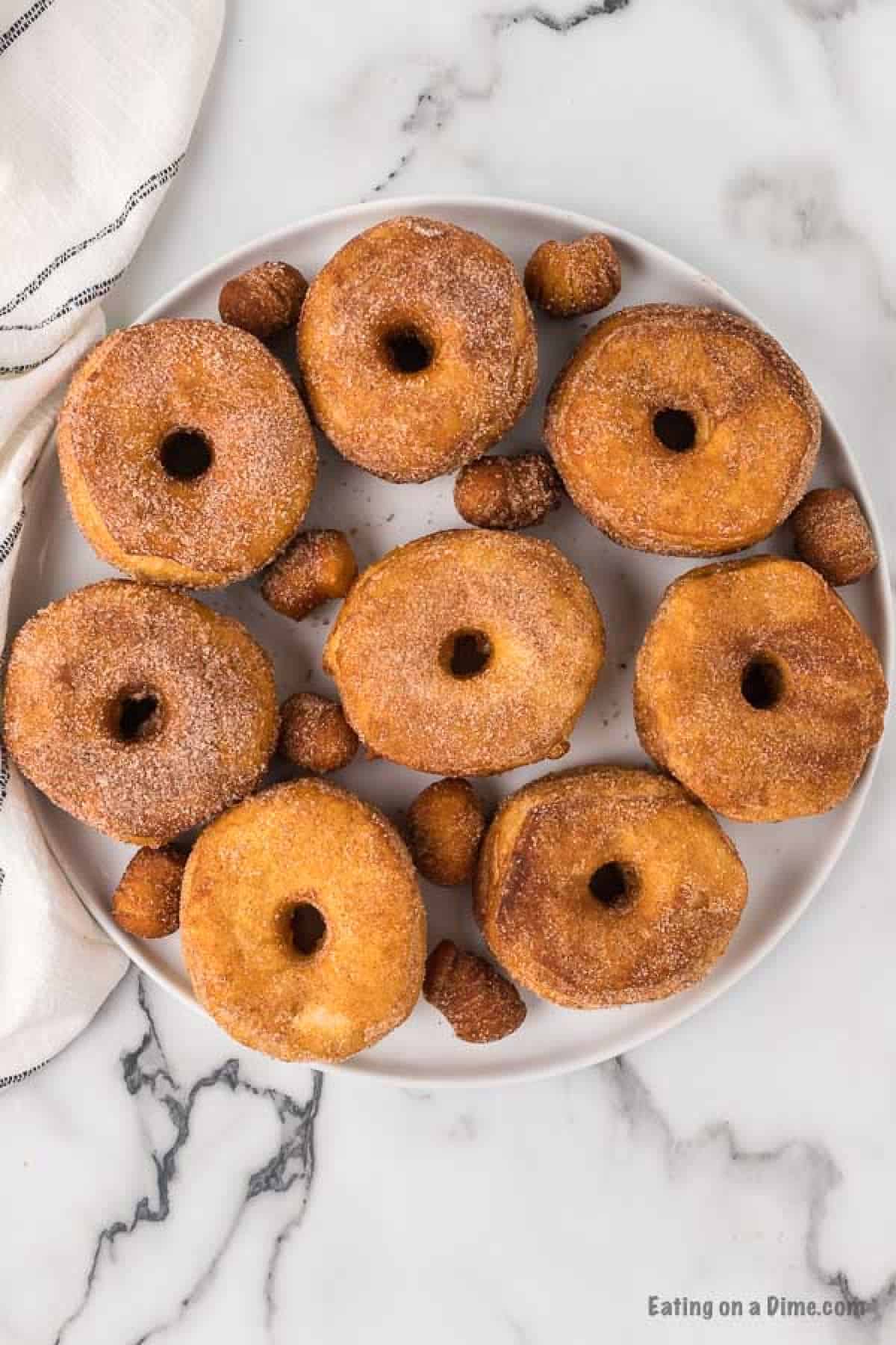 Cooked donuts covered in cinnamon and sugar on a plate.